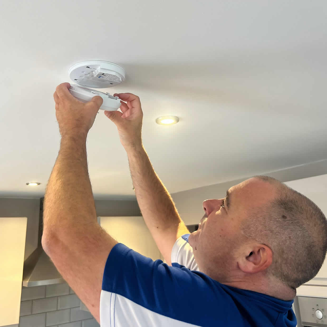 Smoke alarm installer fitting an alarm in an Altrincham property